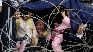 A little girl cries as she tries to take shelter from the rain on Greece's border with Macedonia Photo Reuters