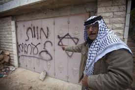 A Palestinian man points to Hebrew graffiti reading “Death to the Arabs” following an arson attack in Khirbet Abu Falah, northeast of the West Bank city of Ramallah, Sunday, Nov. 23, 2014. Source Ma'an News.